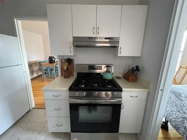 kitchen featuring white refrigerator, stainless steel range with gas stovetop, white cabinets, and light hardwood / wood-style flooring