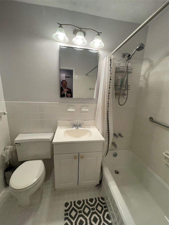 full bathroom featuring tile walls, shower / tub combo, vanity, a textured ceiling, and toilet