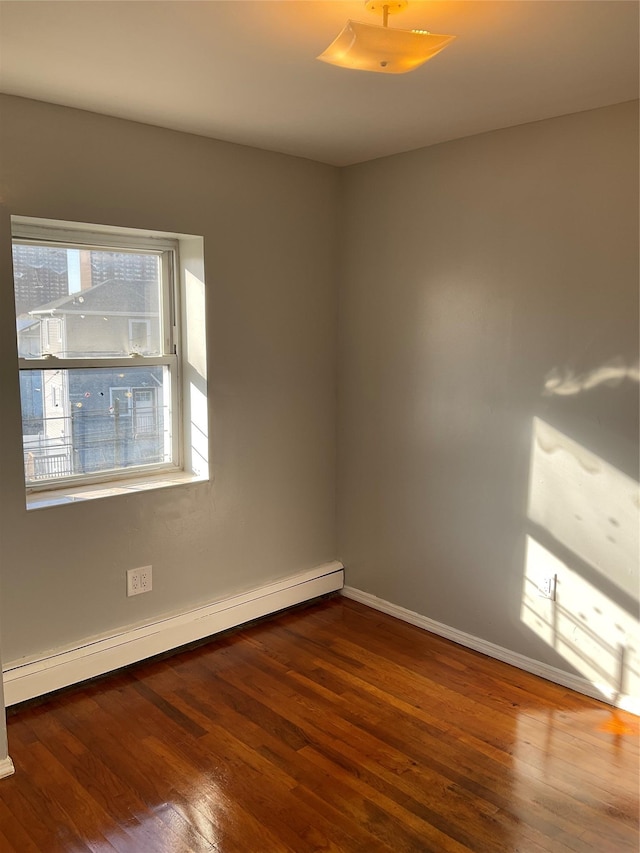 empty room featuring hardwood / wood-style flooring and a baseboard radiator