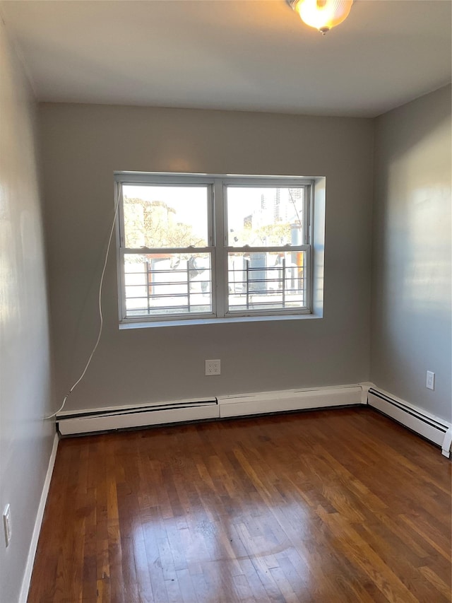 empty room with dark hardwood / wood-style floors and baseboard heating