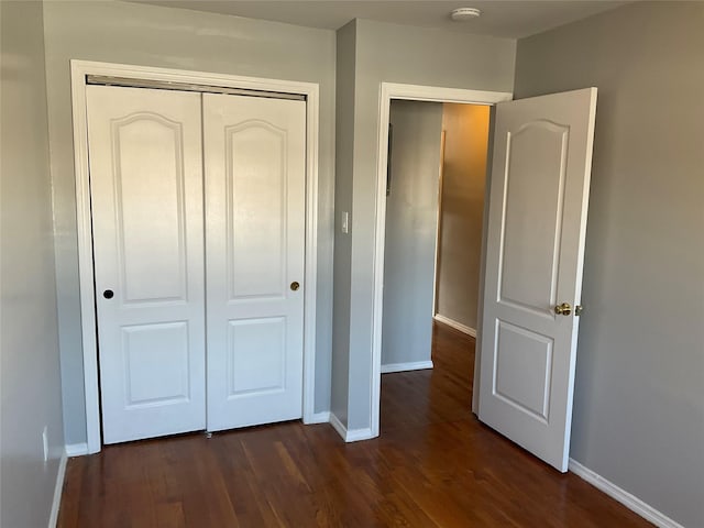 unfurnished bedroom featuring dark wood-type flooring and a closet