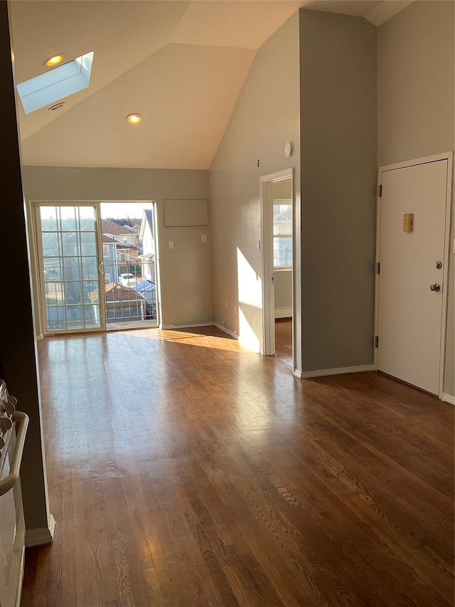 unfurnished living room with hardwood / wood-style flooring, high vaulted ceiling, and a skylight