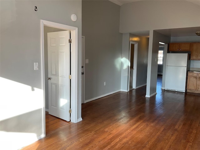 unfurnished living room with dark hardwood / wood-style flooring and a high ceiling