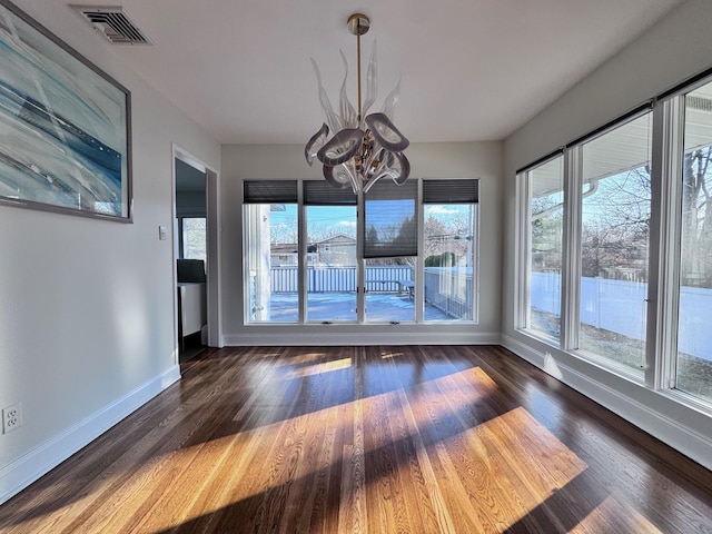 interior space featuring an inviting chandelier, a wealth of natural light, and dark hardwood / wood-style flooring