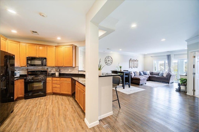 kitchen with visible vents, light wood-type flooring, backsplash, black appliances, and dark countertops