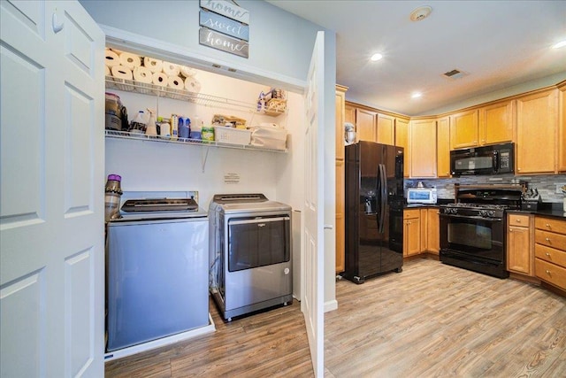 kitchen featuring black appliances, separate washer and dryer, visible vents, and light wood-style floors