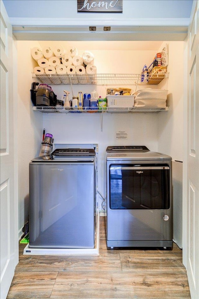 clothes washing area with washing machine and clothes dryer and wood finished floors