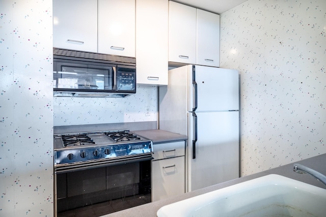 kitchen featuring sink, black appliances, and white cabinets