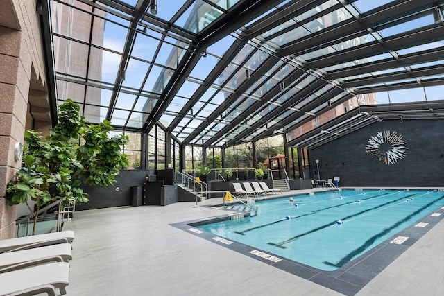 view of swimming pool featuring a patio and glass enclosure