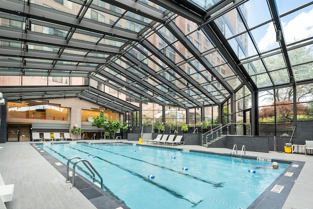 view of swimming pool featuring a patio and glass enclosure