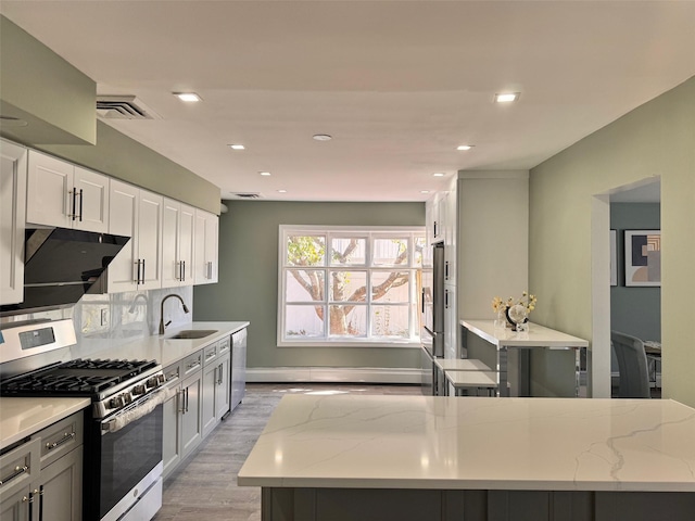 kitchen featuring appliances with stainless steel finishes, sink, white cabinets, and light stone counters