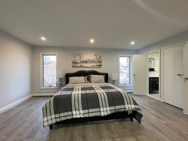 bedroom with light hardwood / wood-style floors and baseboard heating