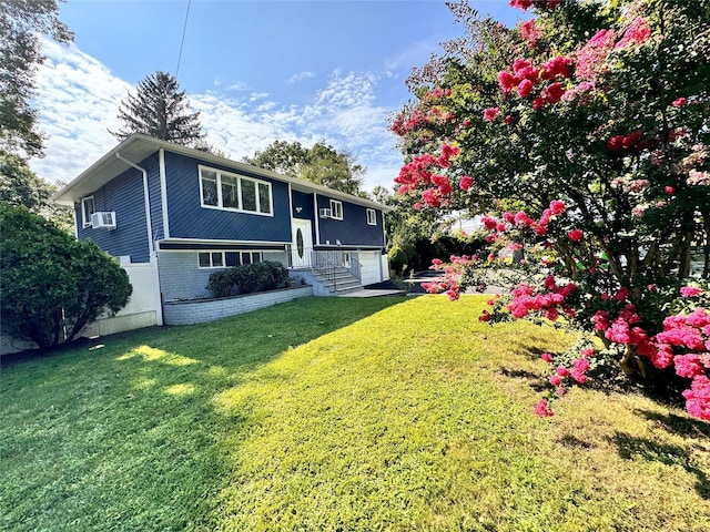 raised ranch featuring a garage, cooling unit, and a front lawn