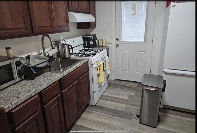 199 Dartmouth St, Hempstead, NY 11550 - kitchen with sink, white appliances, light stone counters, wall chimney range hood, and light wood-type flooring