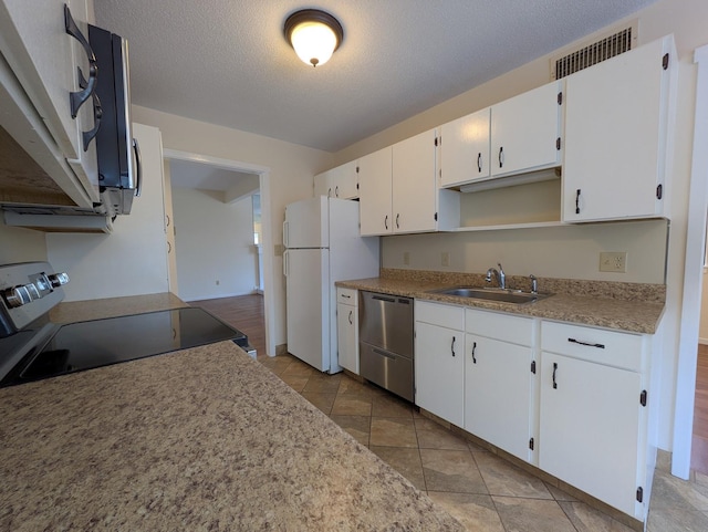 kitchen with appliances with stainless steel finishes, sink, white cabinets, light tile patterned floors, and a textured ceiling