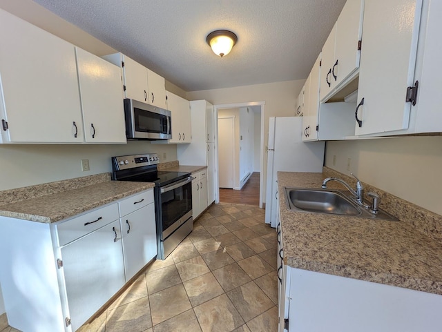 kitchen with stainless steel appliances, sink, a textured ceiling, and white cabinets