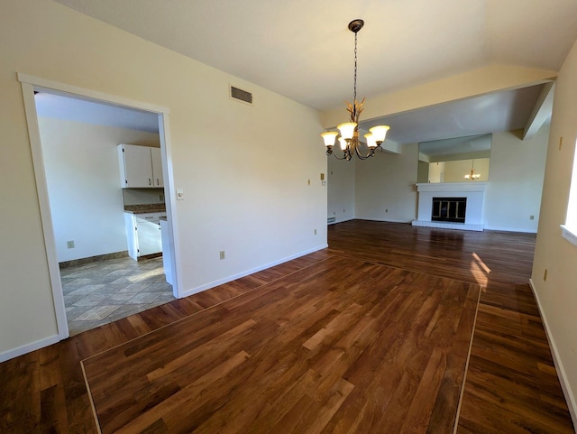 unfurnished living room with an inviting chandelier and dark hardwood / wood-style flooring