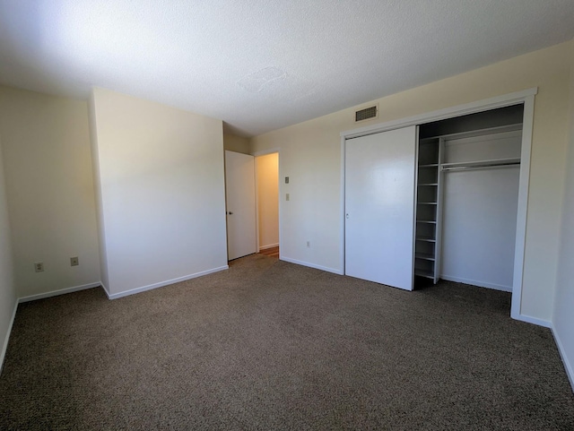 unfurnished bedroom with a closet, dark carpet, and a textured ceiling