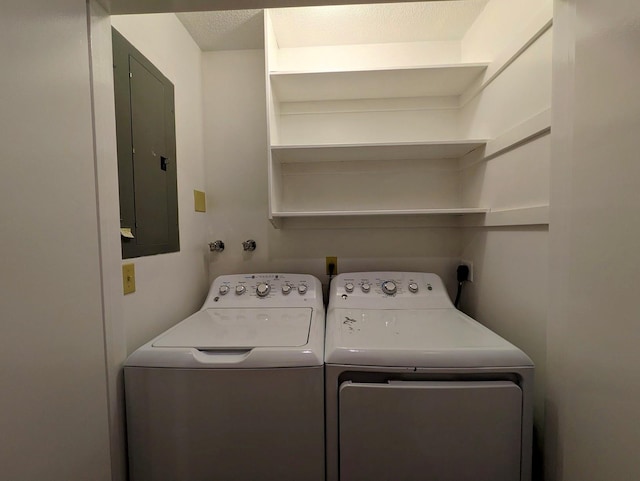 washroom with washing machine and clothes dryer, electric panel, and a textured ceiling