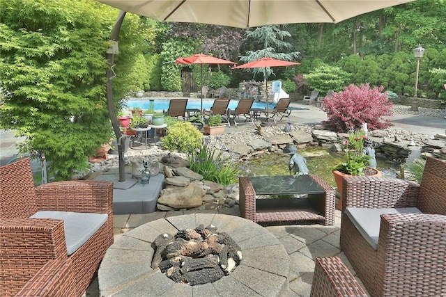 view of patio with an outdoor fire pit and an outdoor pool