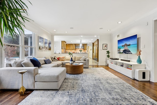 living room with baseboards, ornamental molding, wood finished floors, and recessed lighting