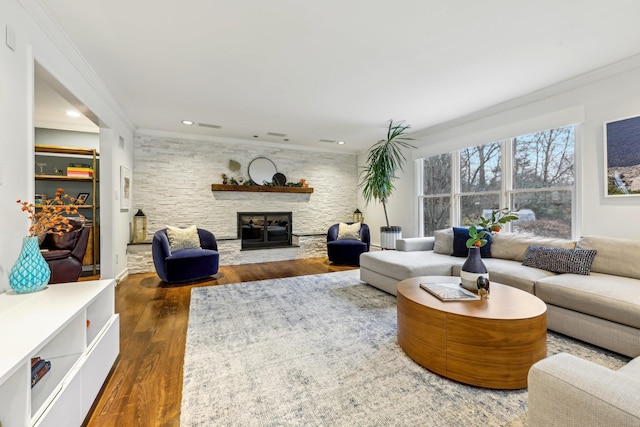 living room with recessed lighting, crown molding, a stone fireplace, and wood finished floors