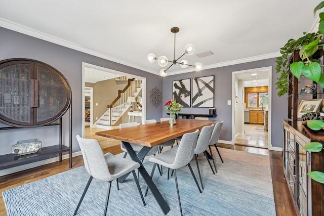 dining space featuring an inviting chandelier, crown molding, stairs, and wood finished floors