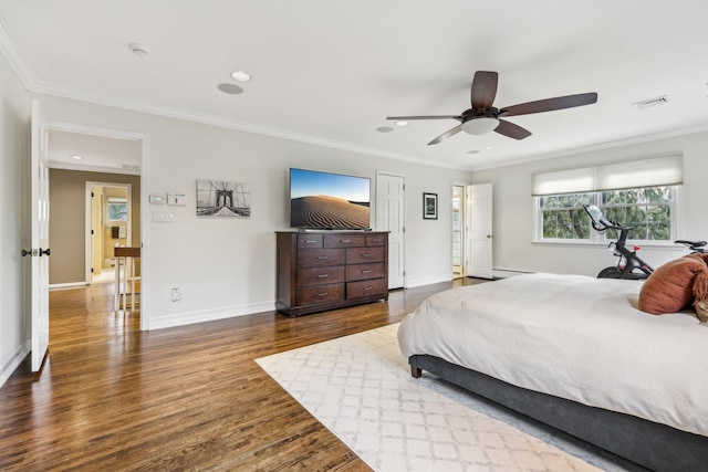 bedroom featuring ornamental molding, visible vents, baseboards, and wood finished floors