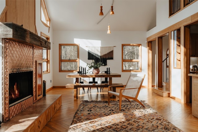 dining room featuring a tile fireplace, light hardwood / wood-style floors, and a high ceiling