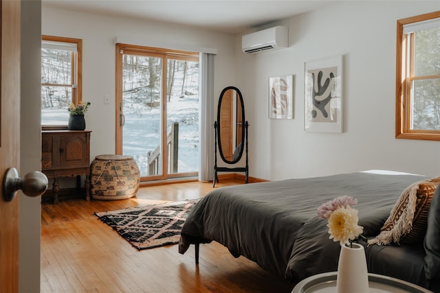 bedroom featuring a wall mounted air conditioner, access to exterior, and light hardwood / wood-style flooring