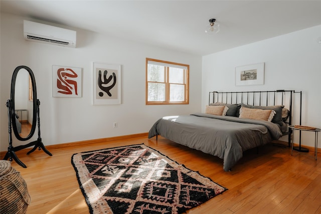 bedroom with a wall mounted air conditioner and hardwood / wood-style floors