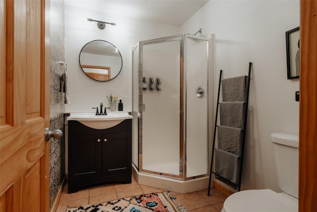 bathroom with vanity, toilet, a shower with shower door, and tile patterned flooring