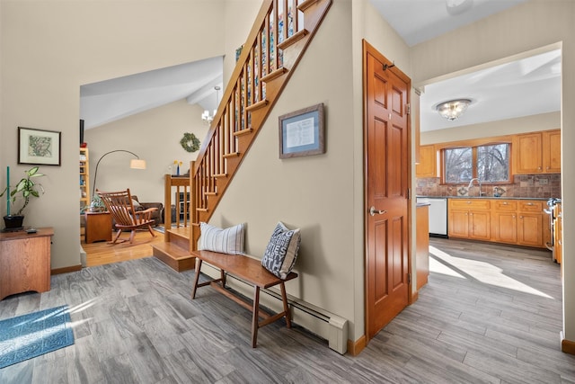 interior space with sink, lofted ceiling, a baseboard radiator, and wood-type flooring