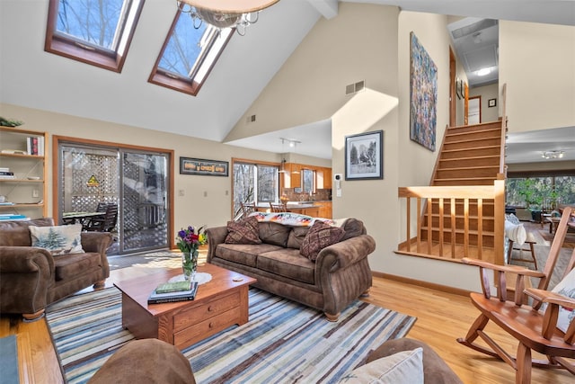 living room with beam ceiling, light hardwood / wood-style flooring, high vaulted ceiling, and a skylight