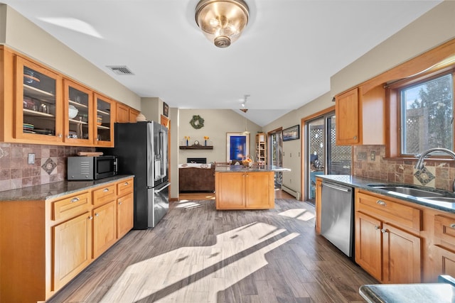 kitchen featuring appliances with stainless steel finishes, wood-type flooring, lofted ceiling, a kitchen island, and sink