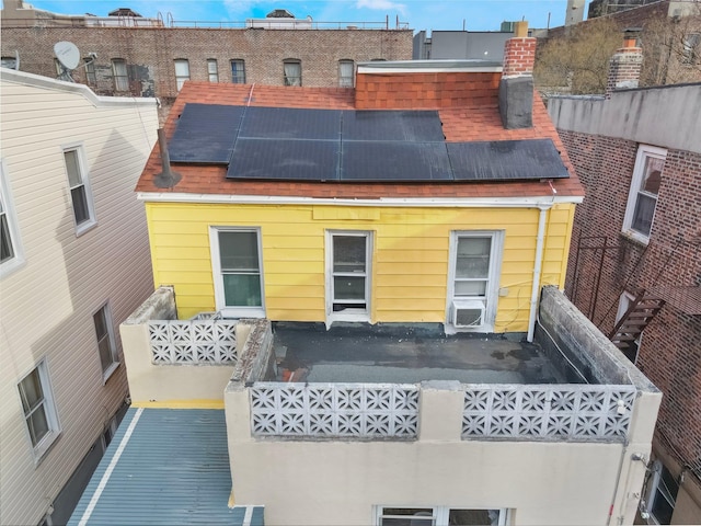 rear view of house featuring cooling unit, roof with shingles, and solar panels