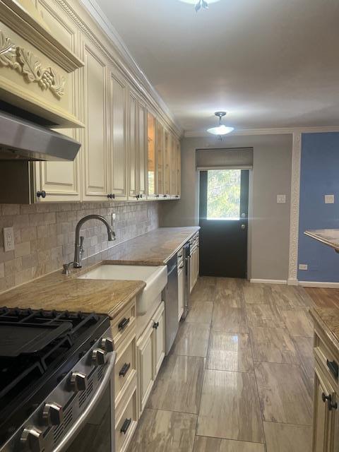 kitchen featuring tasteful backsplash, stainless steel appliances, crown molding, light countertops, and a sink