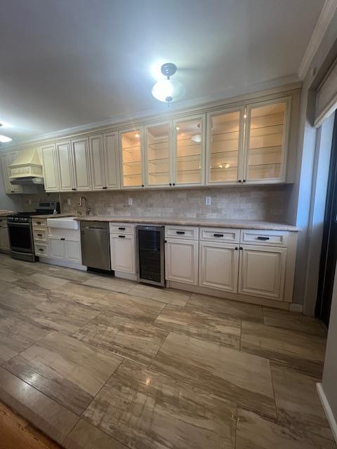 kitchen featuring stainless steel appliances, wine cooler, backsplash, and light countertops