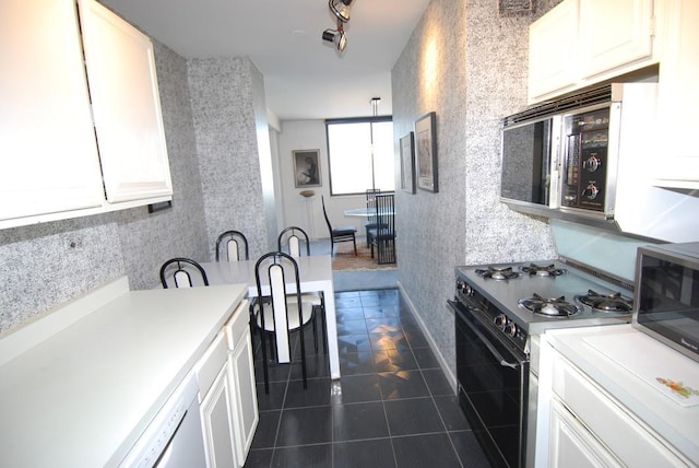 kitchen with dark tile patterned floors, white cabinets, and range with gas cooktop