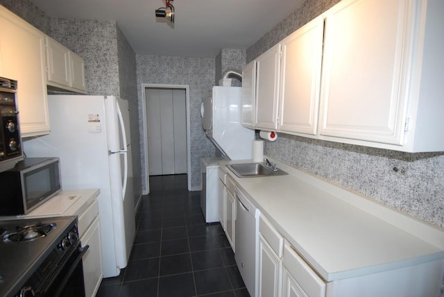 kitchen featuring stainless steel appliances, dark tile patterned floors, sink, and white cabinets