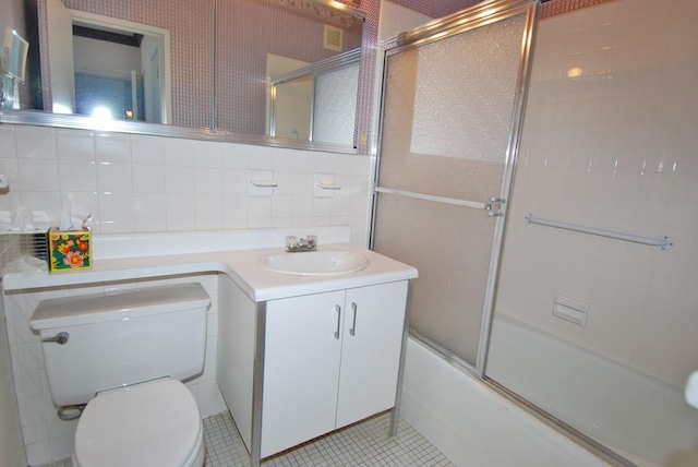 full bathroom featuring tile walls, bath / shower combo with glass door, vanity, tile patterned floors, and toilet