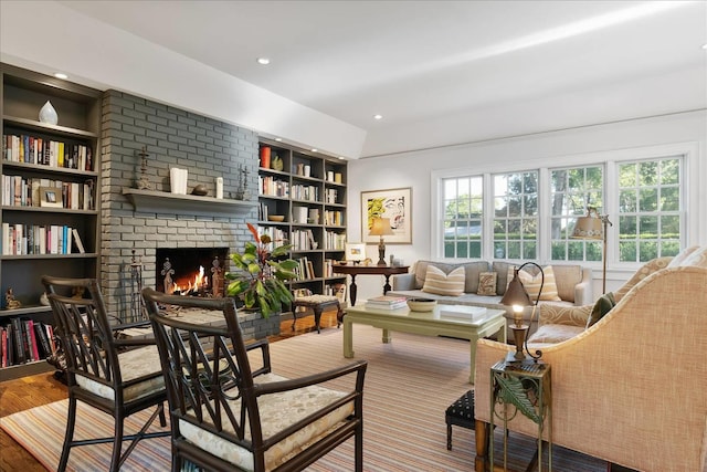 sitting room with hardwood / wood-style flooring, a brick fireplace, and built in features