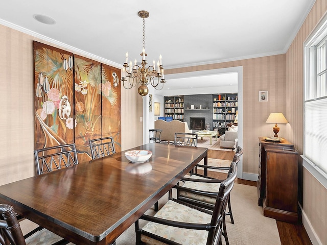 dining space featuring crown molding, a fireplace, a chandelier, and plenty of natural light