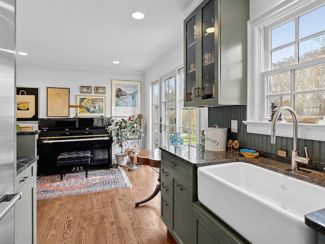 interior space with gray cabinets, sink, dark stone counters, light hardwood / wood-style floors, and crown molding