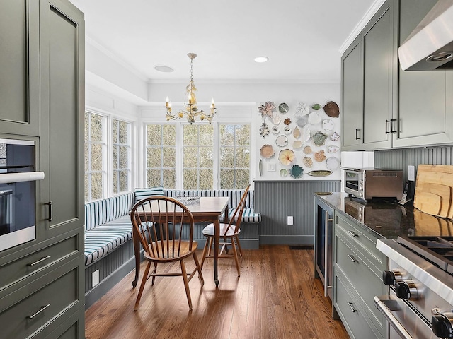 kitchen featuring crown molding, dark wood-type flooring, appliances with stainless steel finishes, gray cabinetry, and wall chimney exhaust hood