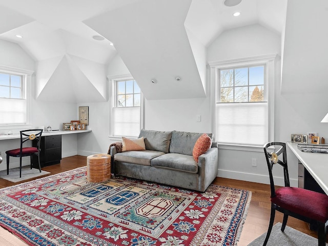 living room with lofted ceiling, built in desk, and hardwood / wood-style floors