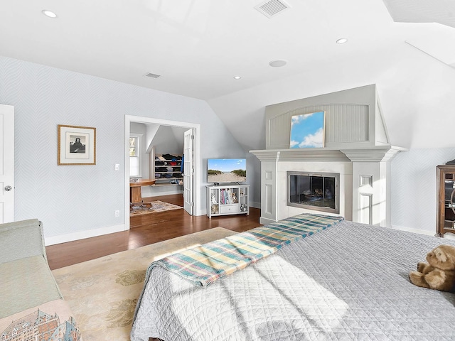 bedroom with a spacious closet, vaulted ceiling, a closet, and wood-type flooring