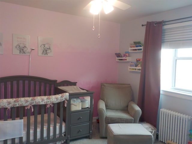 carpeted bedroom featuring a nursery area and radiator