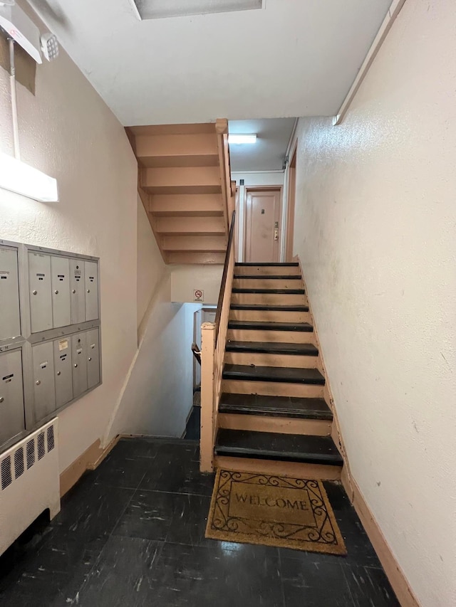 staircase featuring radiator heating unit and a mail area