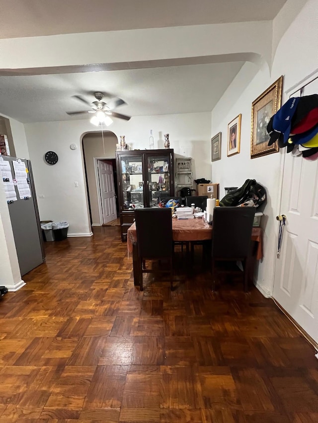 dining space with ceiling fan and dark parquet floors